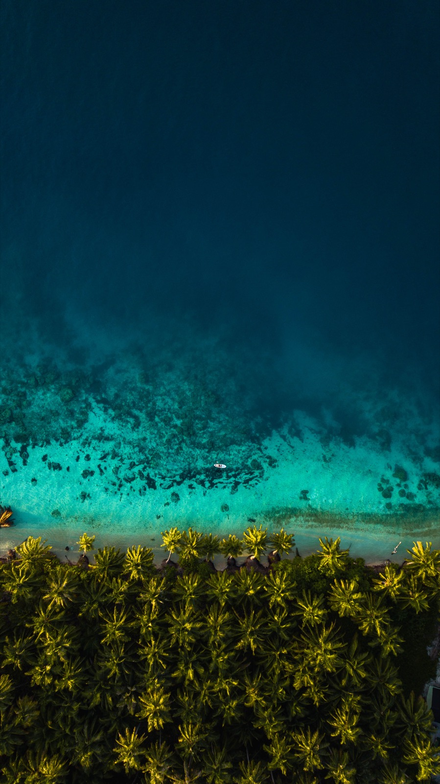 A paddleboarder crossing deep blue water above the Mentawai reef